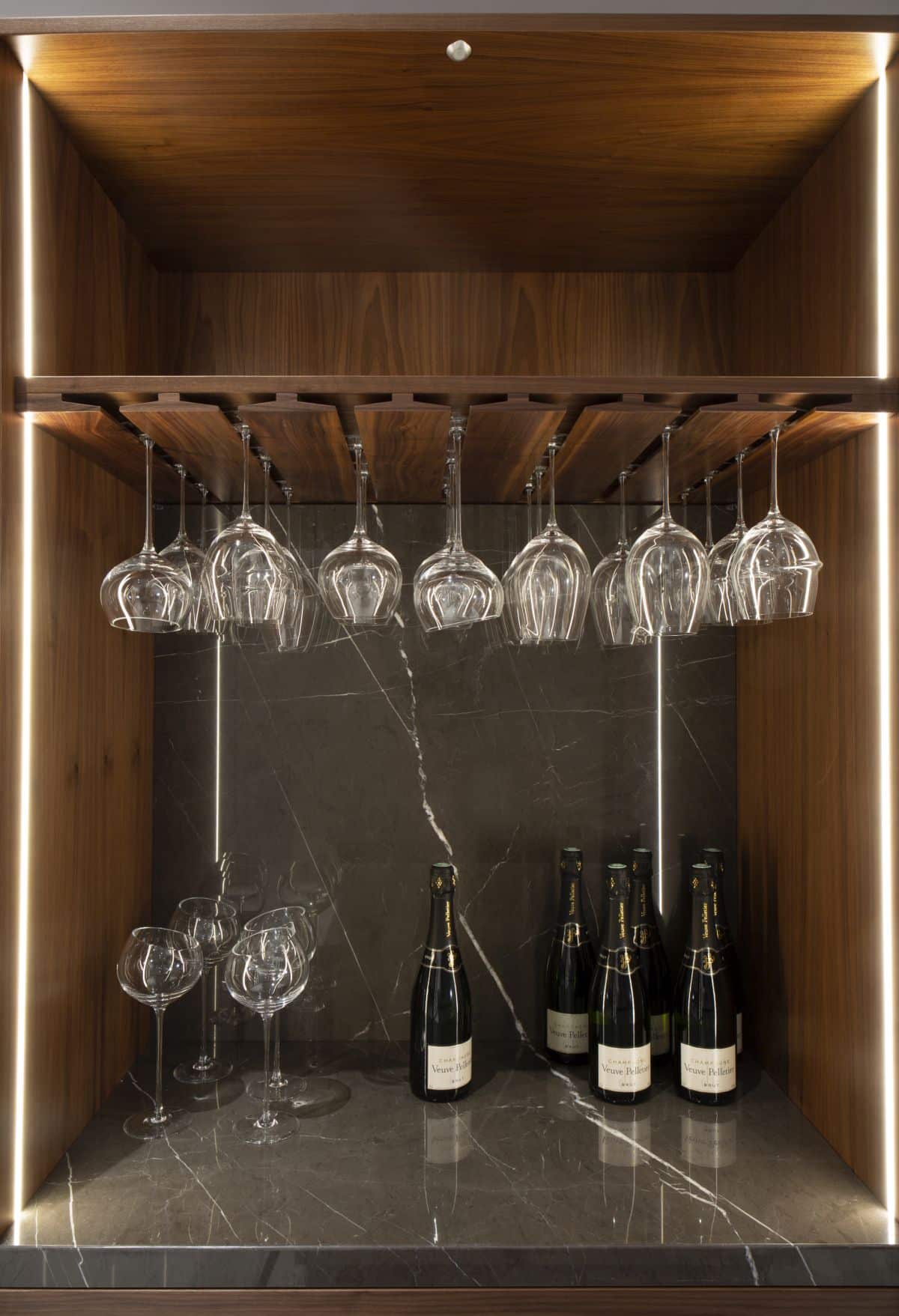 Une élégante étagère en verre est parfaitement intégrée au bar, ajoutant une fonction sans compliquer l'esthétique.