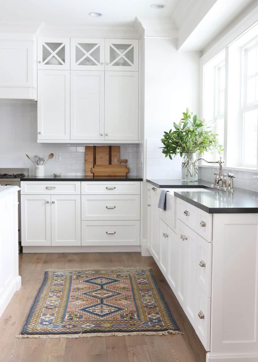 Conception d'une cuisine blanche avec des armoires propres et un comptoir en granit noir.